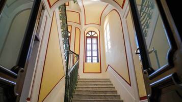Una imponente escalera con detalles de mármol, barandillas ornamentales y un ventanal grande en la parte superior.