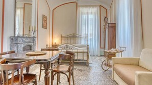 A room with a bed, a dining table with chairs, a chandelier, a fireplace, and a large mirror. - Il Mosaico Family Home near Pompeii (Angri)