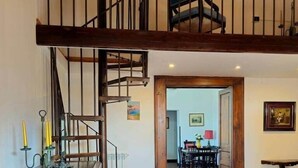 A wooden staircase leading to a loft area with a chair, a dining table, and chairs in the background. - Historic Villa Apartment with Panoramic Views of Mount Vesuvius (Angri)