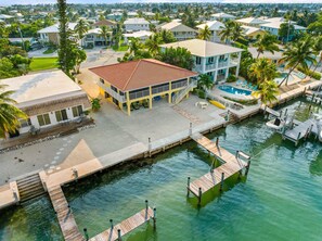 A coastal property with a large house featuring a balcony, a swimming pool, and a dock extending into the water. - Sunset Harbor Waterfront Villa With Dock Cabana Club (Key Colony Beach)
