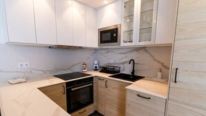 A compact kitchen with a microwave, oven, sink, and cabinets. - First A - La Torre de Suances (Suances)