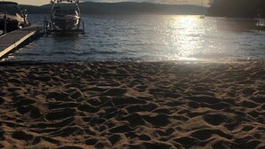 A beach with boats docked, a sandy shore, and a sunset in the background. - LAKE Simon, SPA, private BEACH, 4 bedroom, 2 private office, 10 beds, 16 people. (Lac-Simon)