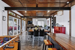 Un comedor moderno con una larga mesa de madera, sillas negras y una zona de bar con un armario rojo.