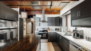 A modern kitchen with stainless steel appliances, dark cabinetry, and a wooden ceiling. - LAKE Simon, SPA, private BEACH, 4 bedroom, 2 private office, 10 beds, 16 people. (Lac-Simon)