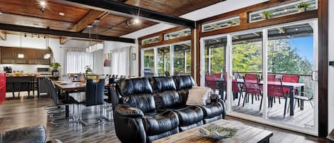 A spacious living area with a leather sofa, dining table, and a view through large glass doors to an outdoor patio.