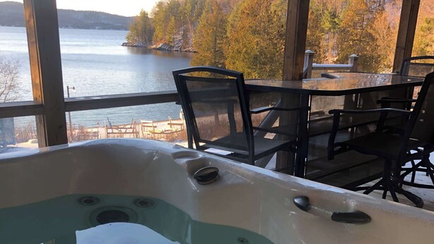 A hot tub with a view of a lake and forest. - LAKE Simon, SPA, private BEACH, 4 bedroom, 2 private office, 10 beds, 16 people. (Lac-Simon)