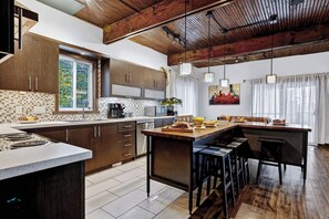 A modern kitchen with a central island, stainless steel appliances, and a large window.
