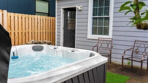 Een hottub in een achtertuin met een houten omheining, een deur en twee stoelen.