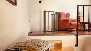 Een gezellige kamer met een bed, een rode fauteuil en een kleine tafel met een lamp.