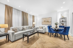 A modern living room with a sofa, armchairs, a coffee table, and a dining area with chairs and a table.