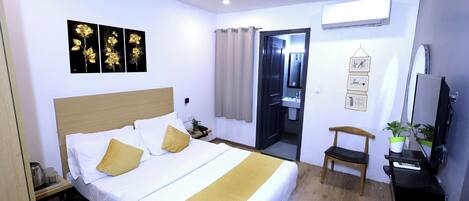 Una habitación de hotel con cama, escritorio, computadora, silla y televisor.