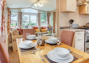 A dining area with a table set for four, a kitchen with modern appliances, and a view of the outdoors. - 2 bedroom accommodation in Bala, (Bala,)