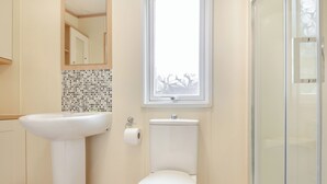 Et badeværelse med vask, toilet og et vindue.