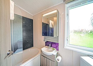 Ein Badezimmer mit Badewanne, Waschbecken, Spiegel und Fenster.