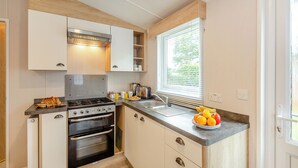 Een praktische keuken met een gasfornuis, oven en een raam met zonwering.