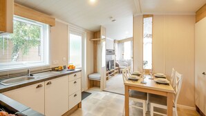 Een moderne keuken met een eethoek, houten kastjes en een groot raam.