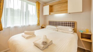 Een hotelkamer met een bed, nachtkastje, gordijnen en hoofdeinde.