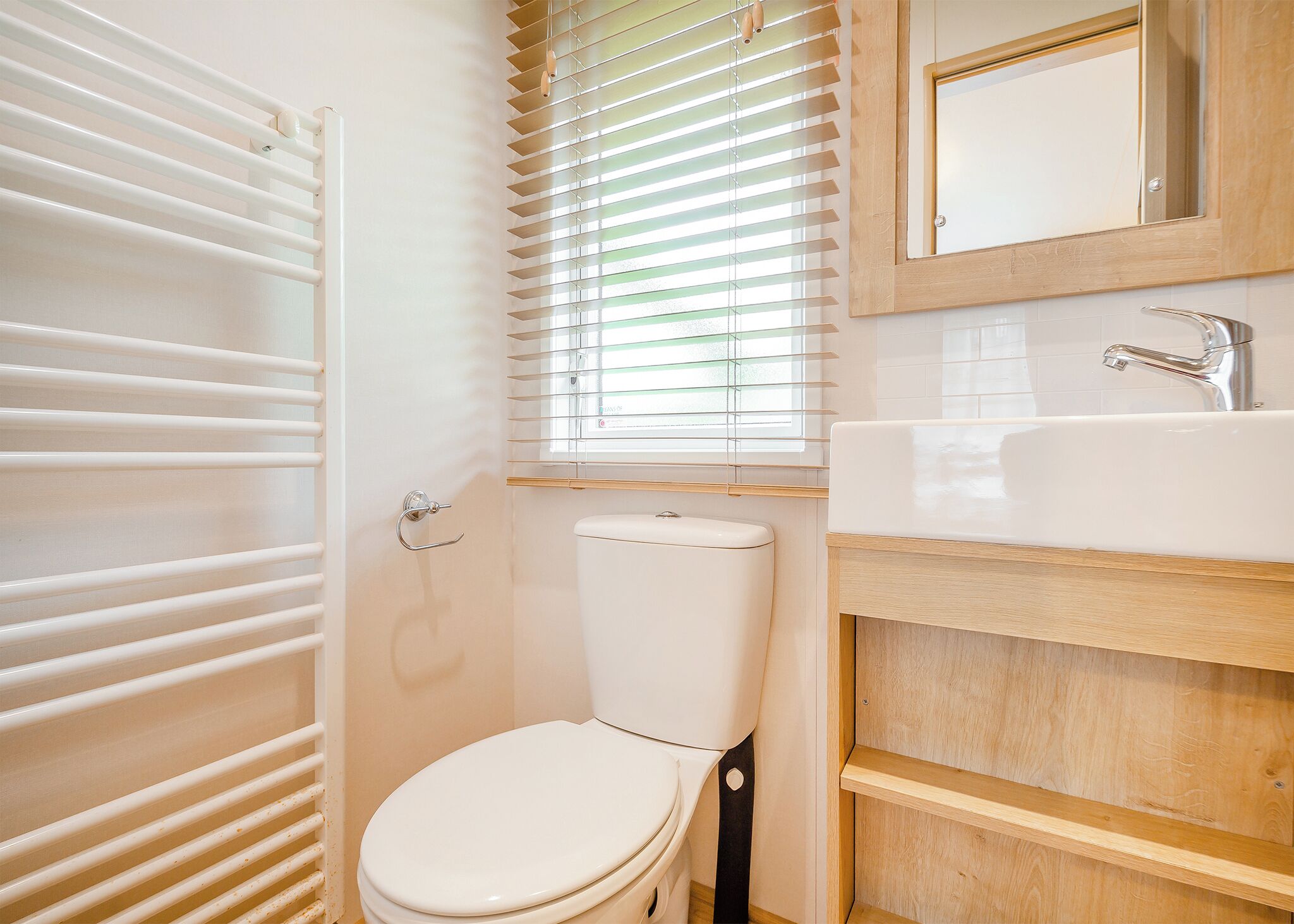 Un baño con inodoro, lavamanos y ventana con persianas.