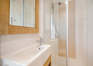 A bathroom with a white sink, a mirror, and a shower with a glass door. - Foxglove 4 Platinum (Pet) (Bala,)