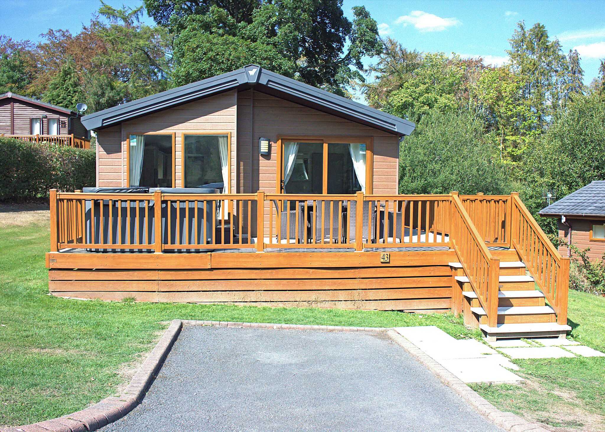 A wooden cabin with a deck and a ramp leading to the entrance.