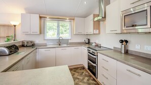 Een moderne keuken met een inbouwoven, roestvrijstalen apparatuur en een raam met zonwering.