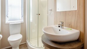 Een badkamer met toilet, een douchecabine en een wastafel met spiegel erboven.