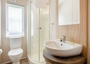 A bathroom with a toilet, a glass-enclosed shower, and a sink with a mirror above it. - Foxglove 6 Platinum (Pet) (Bala,)