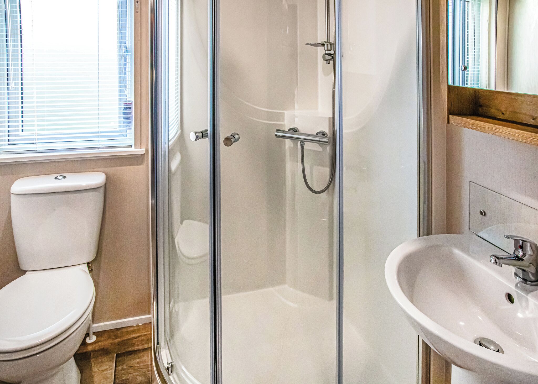 Une salle de bain comprenant des toilettes, une douche fermée par des parois de verre et un lavabo.