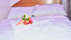 A bed with white bedding and a floral arrangement on it. - Michamvi Holiday Homes (Michamvi)