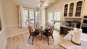 A dining area with a round table and chairs, a ceiling fan, and a kitchen with cabinets and a countertop. - Sosegado Place Hot springs Village (Hot Springs Village)