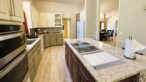 A modern kitchen with a central island, stainless steel appliances, and light-colored cabinetry. - Sosegado Place Hot springs Village (Hot Springs Village)