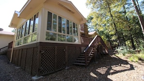 A two-story building with large windows, a wooden deck, and a staircase leading to the upper level. - Sosegado Place Hot springs Village (Hot Springs Village)