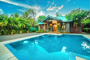 A house with a swimming pool, surrounded by lush greenery. - Lavika Stays Villa Palmera (Alibag)