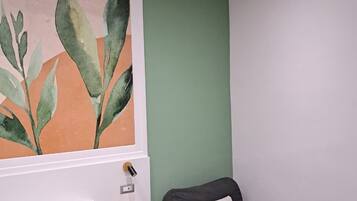 Une pièce avec un lit, une chaise, un grand tableau abstrait et un mur vert.