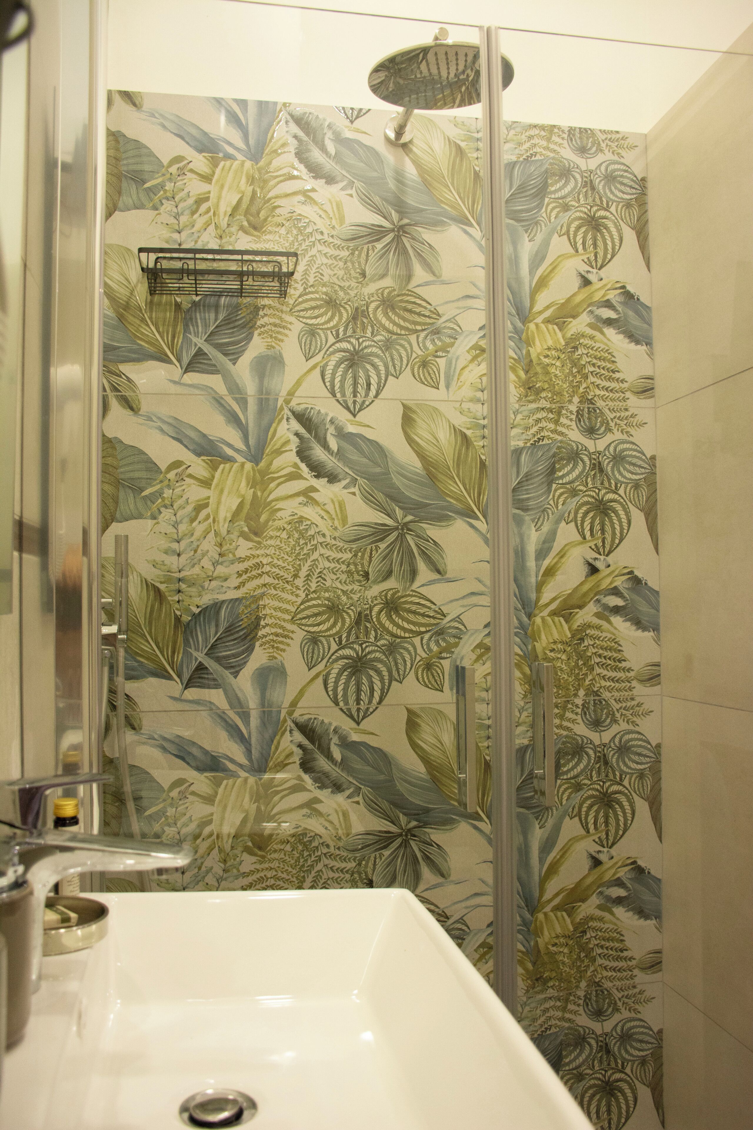A bathroom with a shower enclosure featuring a floral wallpaper design.