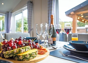 A dining table with a fruit platter, wine glasses, and a bottle of wine. - 2 bedroom accommodation in Bala, (Bala,)