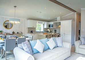 A modern kitchen with white cabinets, a dining area with a white table and grey chairs, and a living room with a white sofa and blue pillows. - 2 bedroom accommodation in Bala, (Bala,)