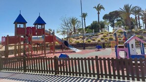 Um parquinho com escorrega, estruturas de escalada e uma casinha.