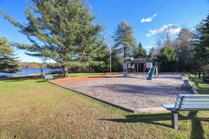 Un parco con un'area giochi, una panchina e un piccolo edificio.