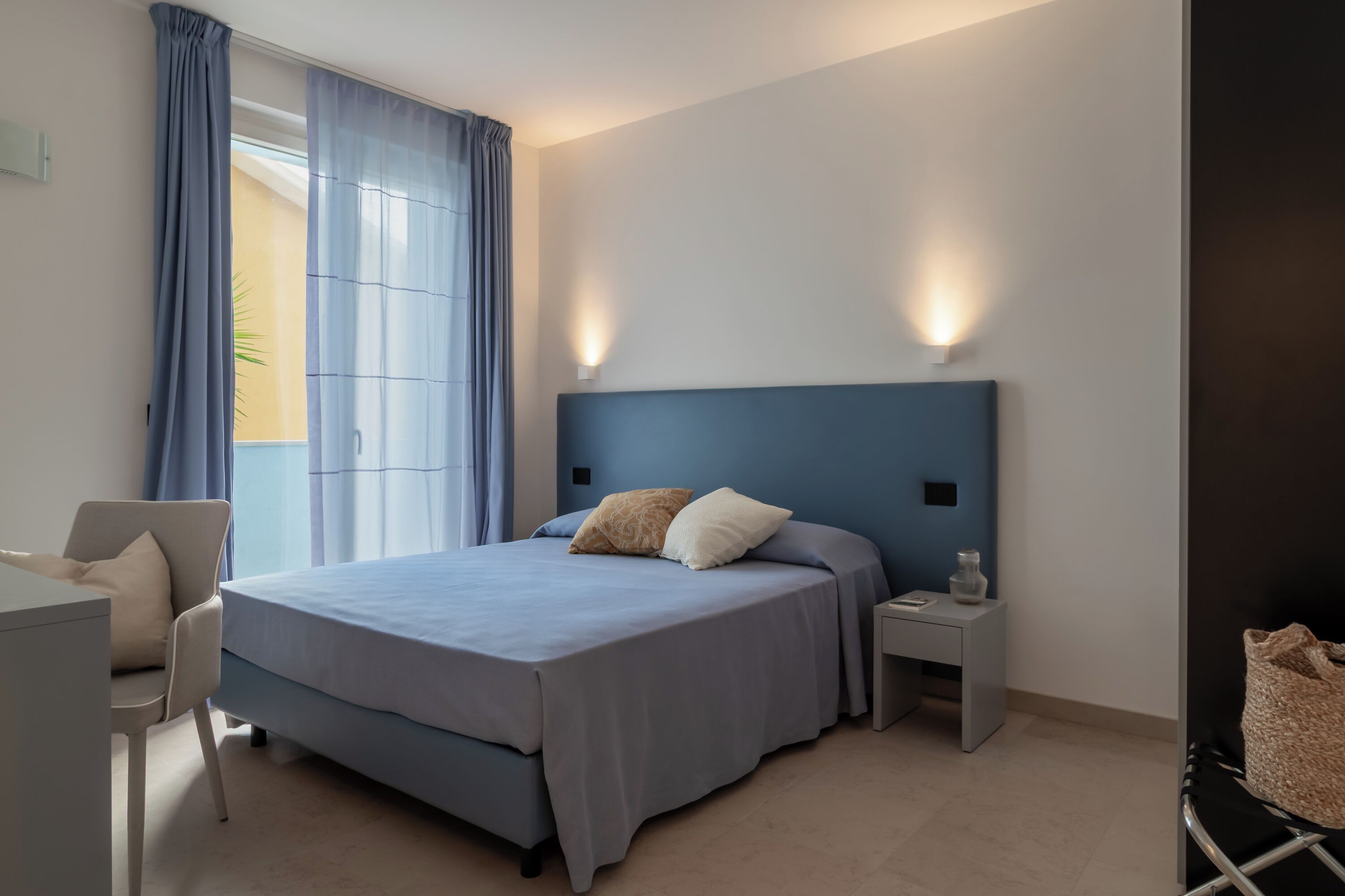 A modern bedroom with a large bed, a desk, and a chair.