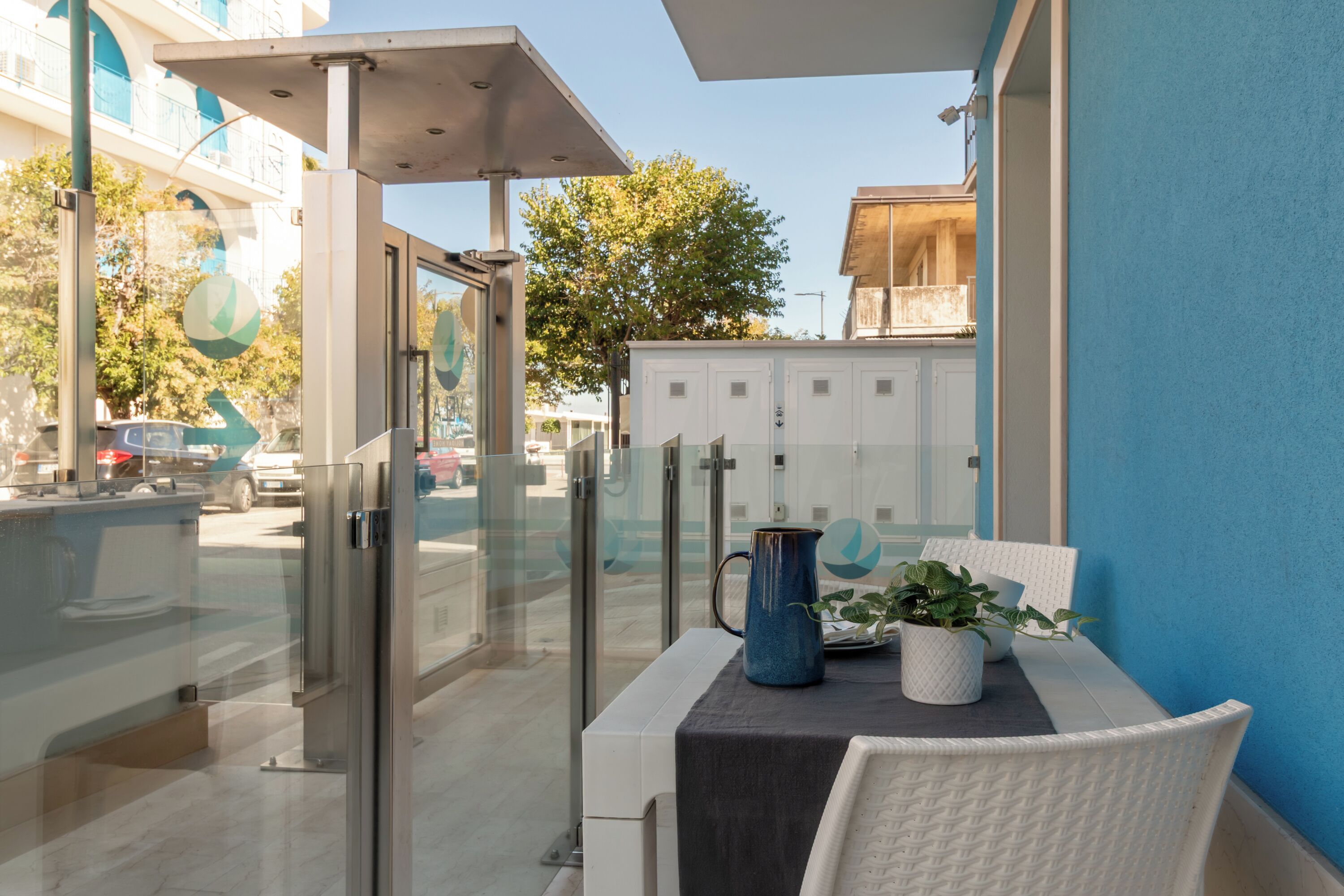 Ein Balkon mit Tisch, Stühlen, einem Blumentopf und einer blauen Karaffe.