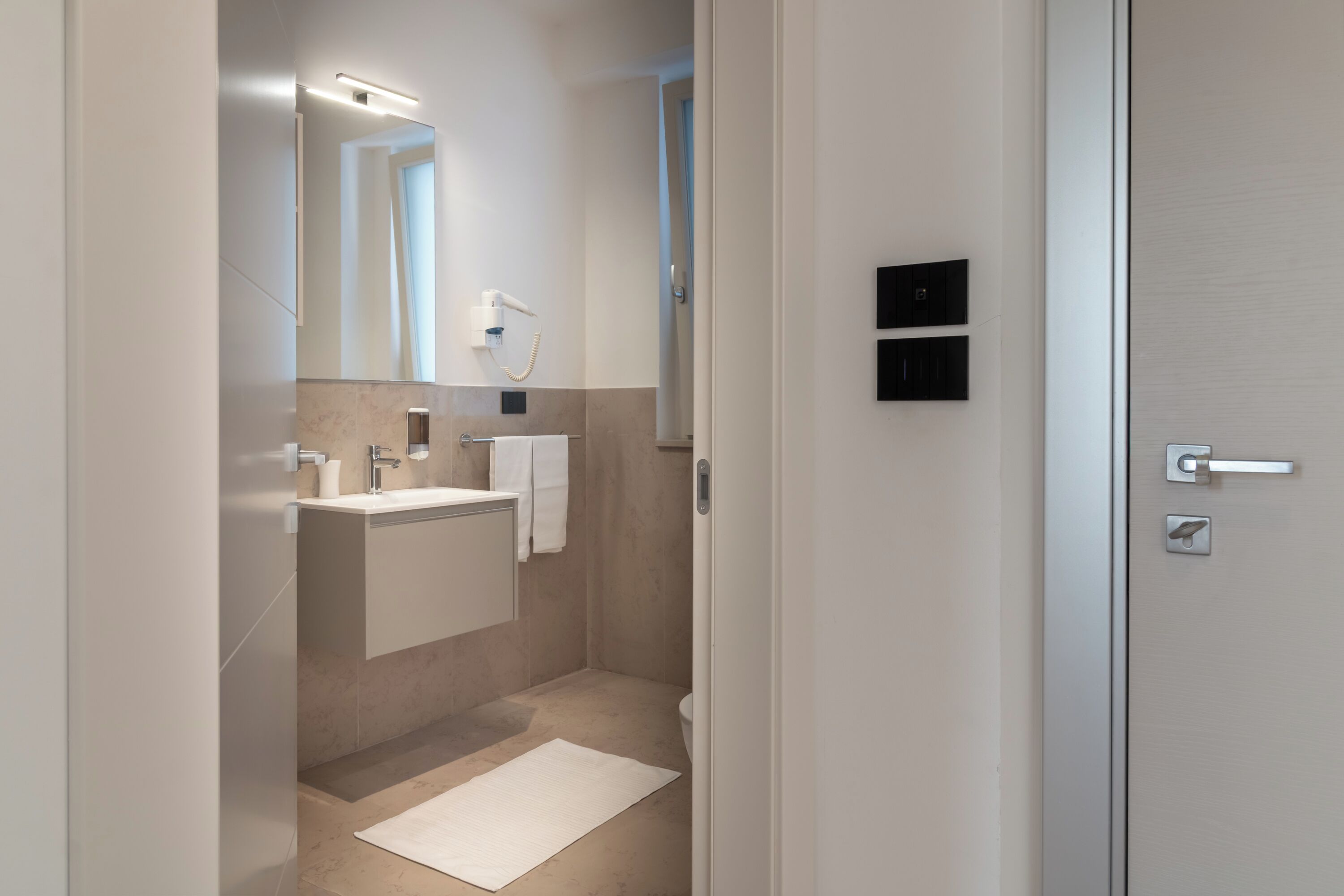 A modern bathroom with a large mirror, a sink, a towel rack, and a shower area.
