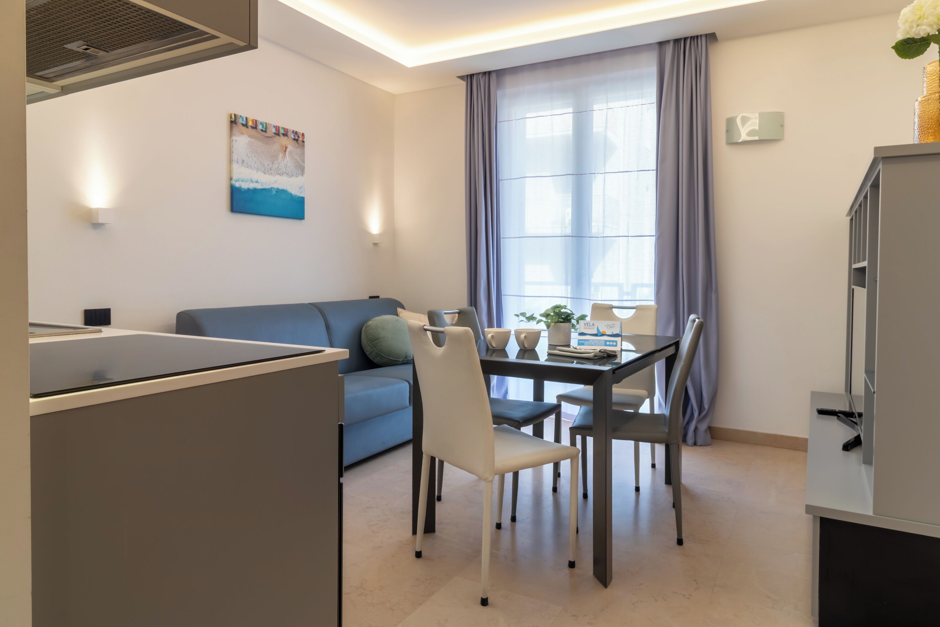 A modern living space with a dining area, a sofa, a table with chairs, and a television.
