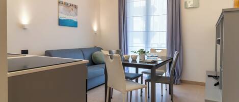 A modern living space with a dining area, a sofa, a table with chairs, and a television.