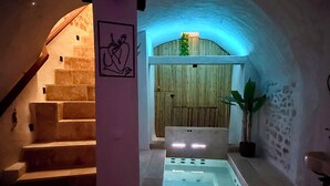 Un área de spa con una escalera de piedra, una puerta de madera y una bañera.