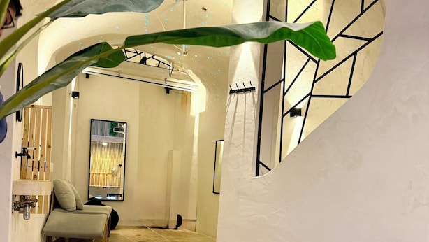 Un área de spa con una bañera de hidromasaje, un banco de madera y un perchero para toallas.