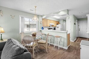 A modern kitchen with wooden cabinets, a central island, and bar stools. - 10% off 3-7 nights thru Dec. 2BR 2BA condo. Walking distance to beach. Pool. (North Myrtle Beach)
