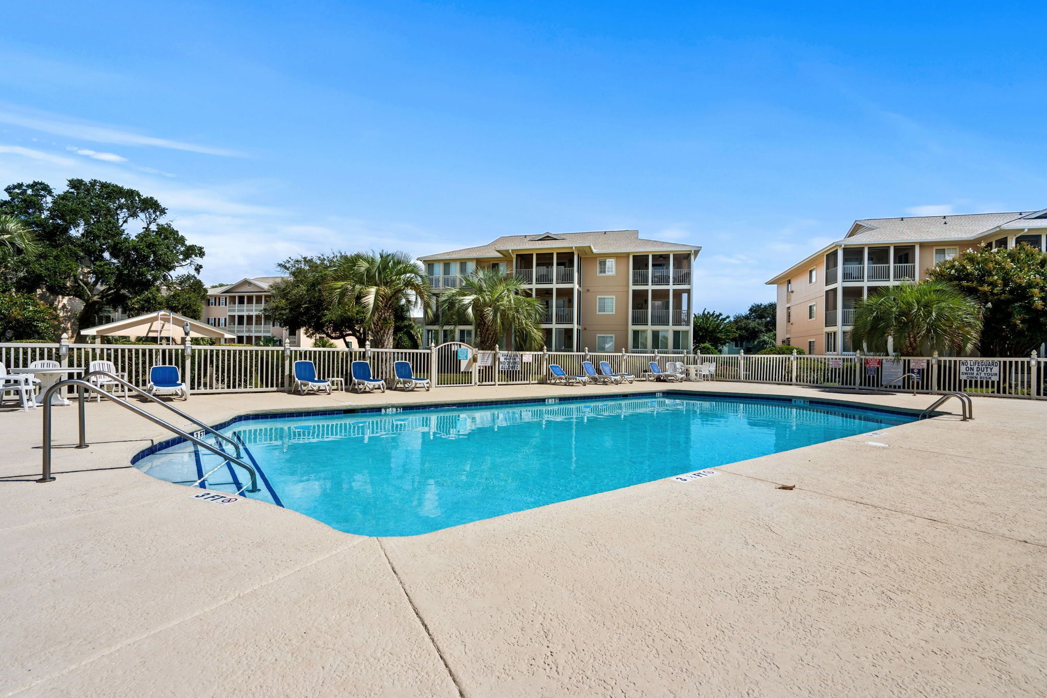 A swimming pool with lounge chairs and a lifeguard stand.