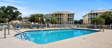 A swimming pool with lounge chairs and a lifeguard stand.