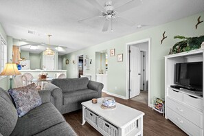 A living room with a grey sofa, white coffee table, and a TV stand. - 10% off 3-7 nights thru Dec. 2BR 2BA condo. Walking distance to beach. Pool. (North Myrtle Beach)